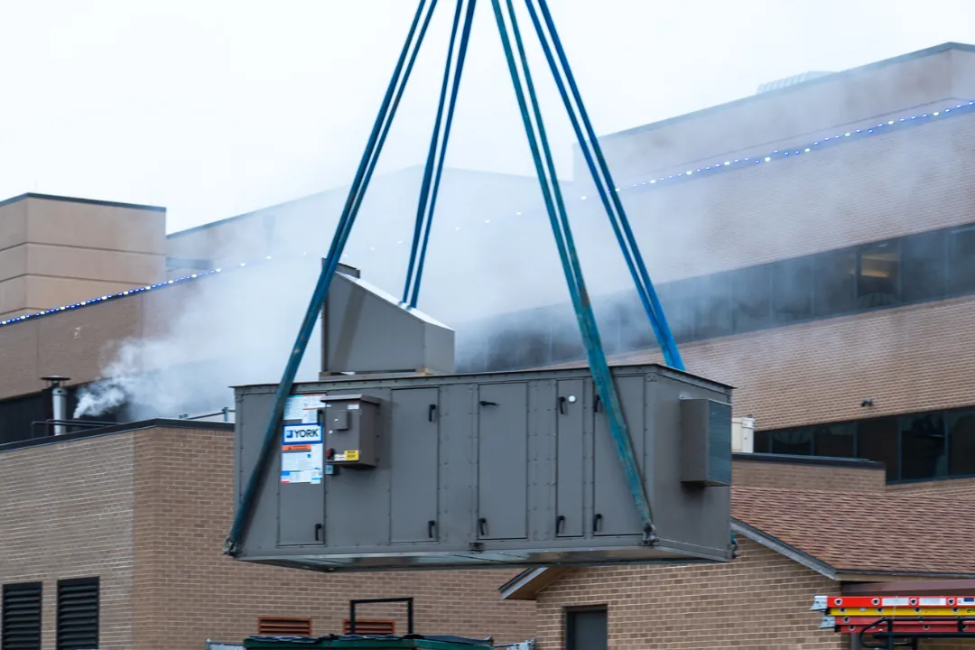 Crane setting a rooftop unit on a commercial building